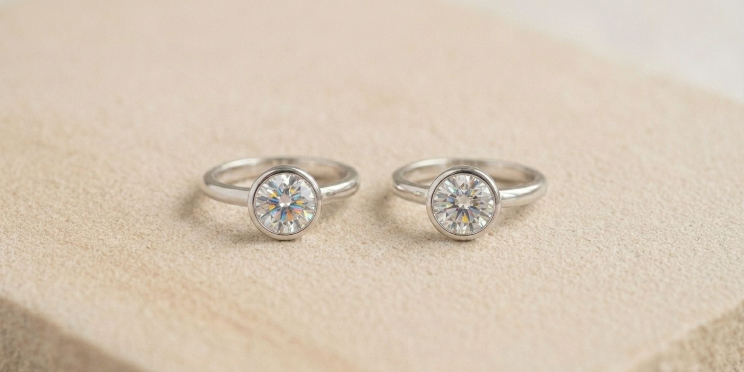Two sterling silver solitaire rings with brilliant colourless stones on marble
