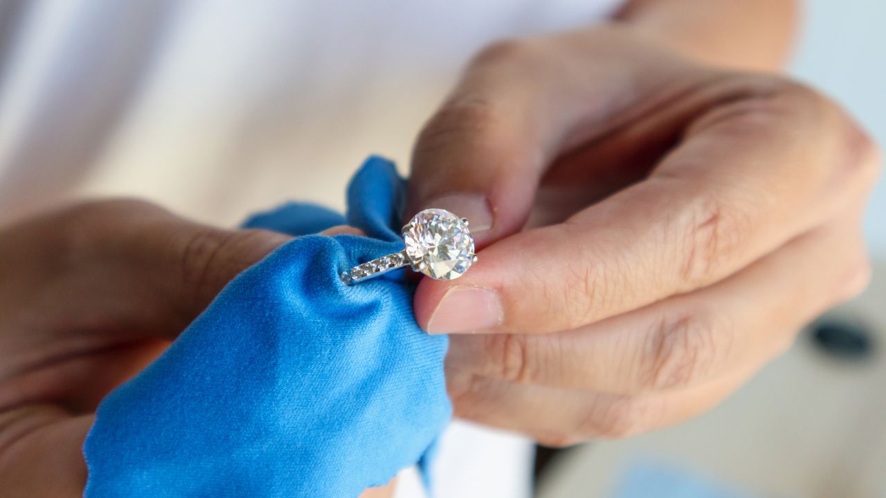 Close-up of a moissanite ring being gently cleaned with a soft cloth
