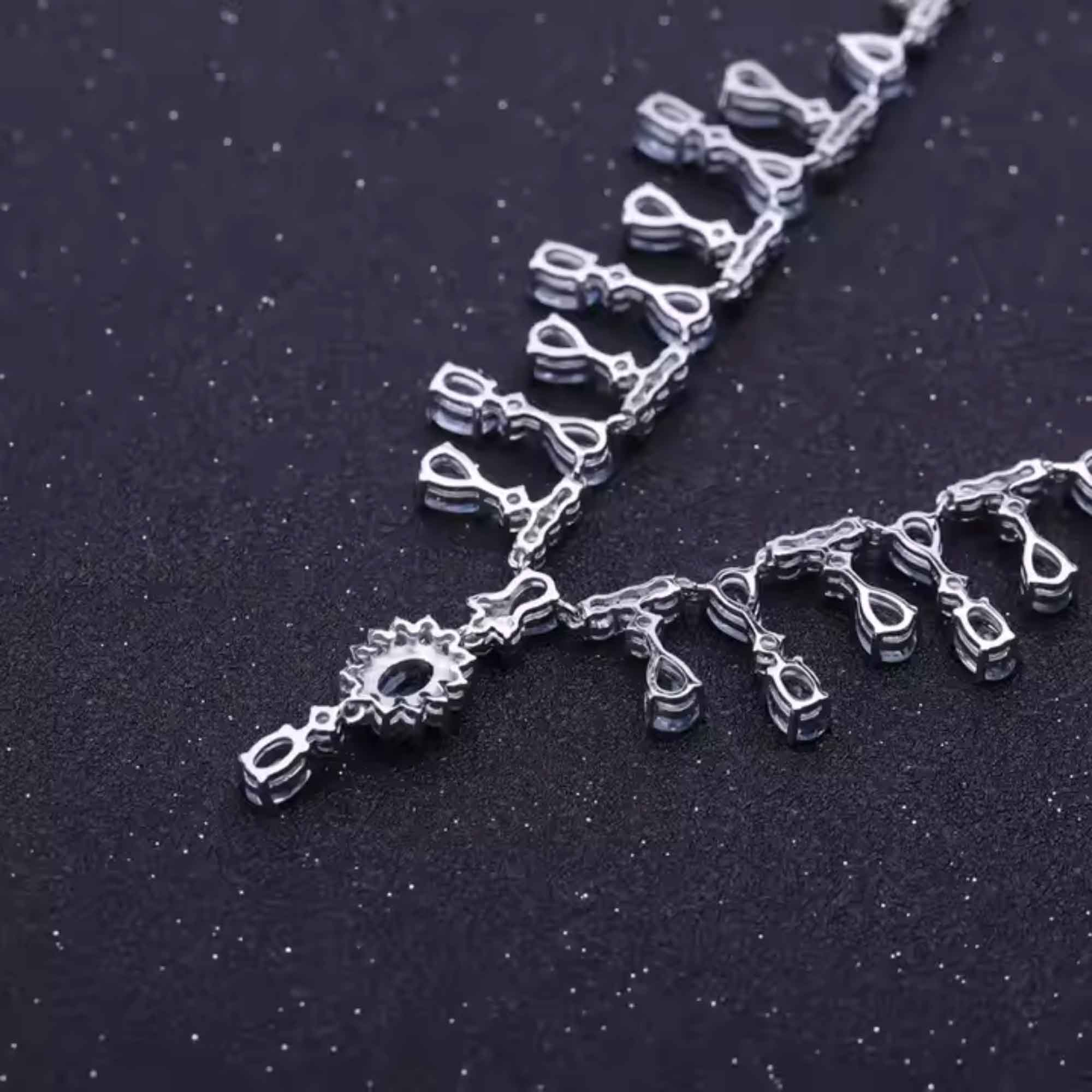 Silver necklace with intricate design on a dark background