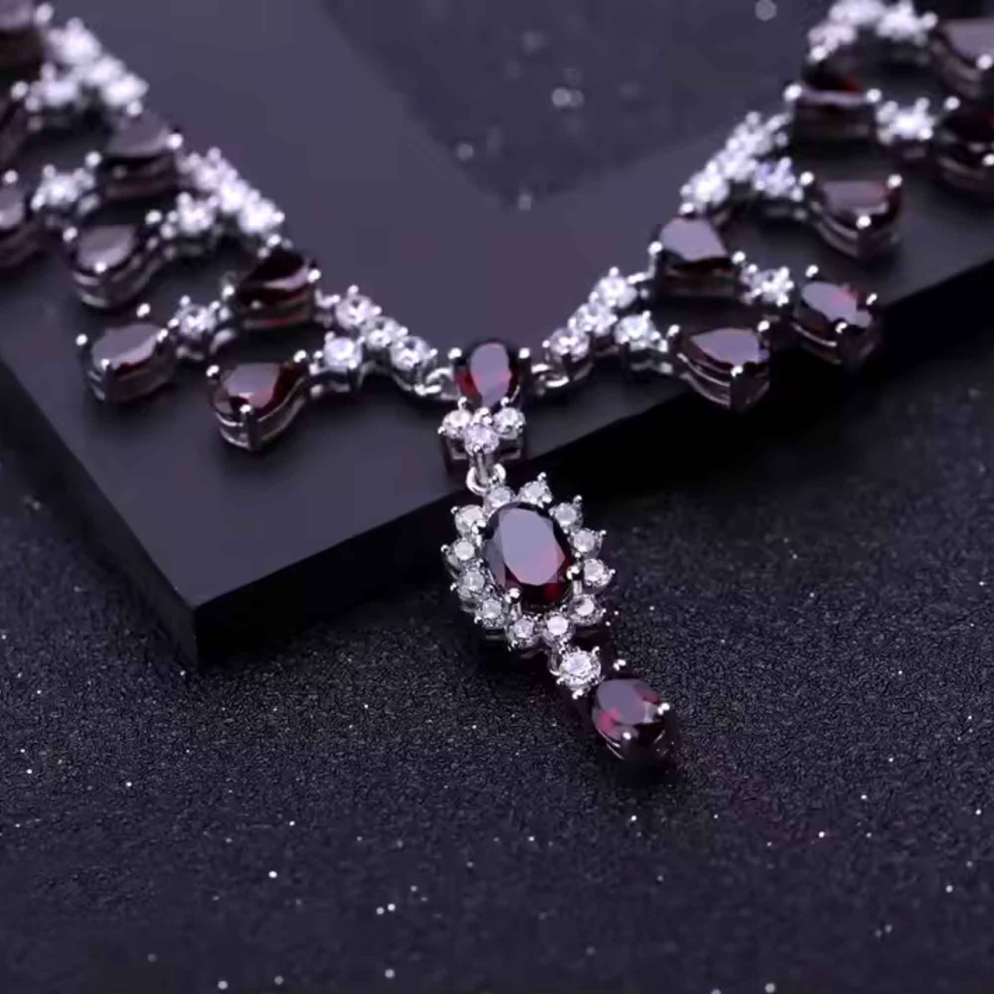 Delicate necklace with red gemstones and silver accents on a dark background