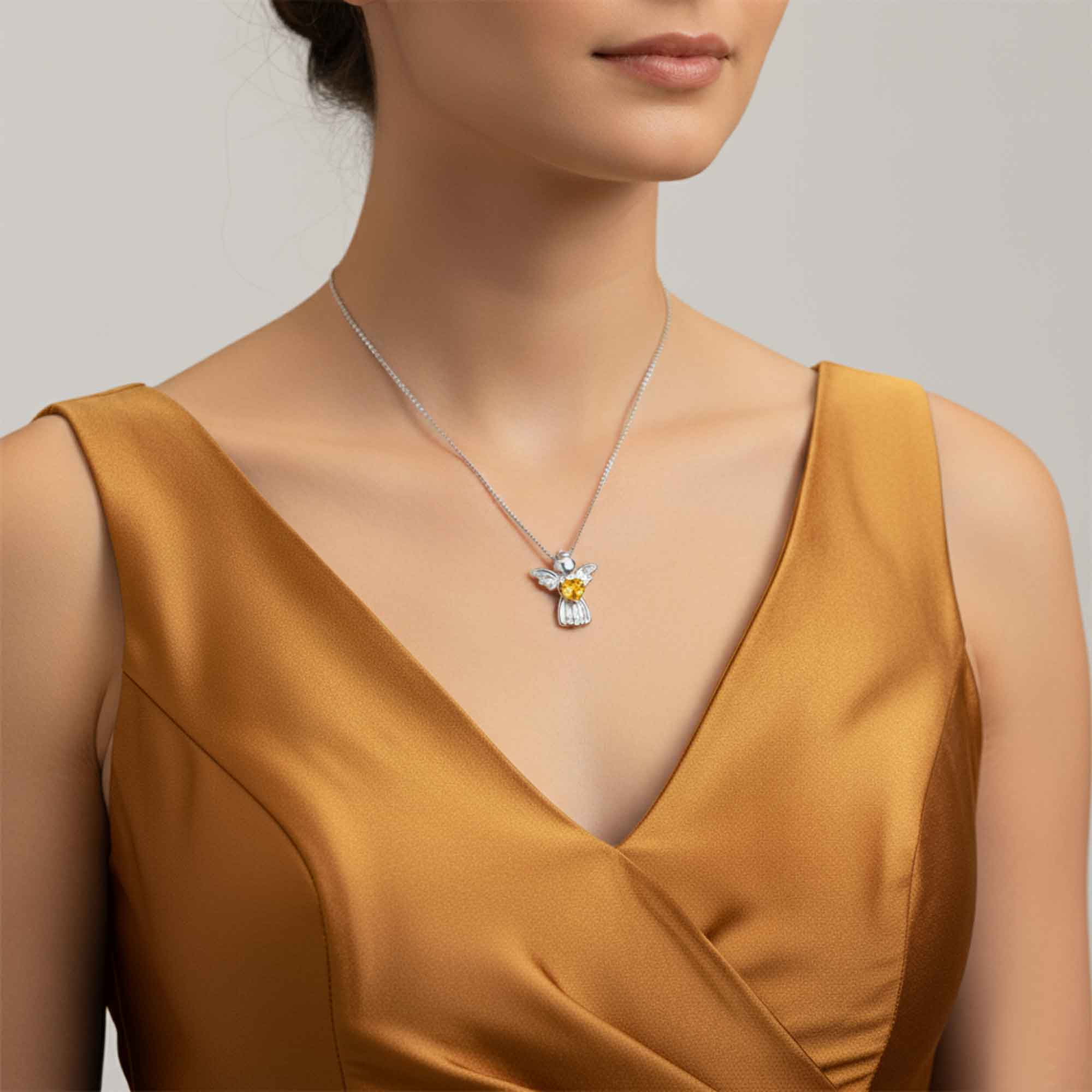 Woman wearing a gold dress with a silver necklace featuring a yellow citrine gemstone pendant.