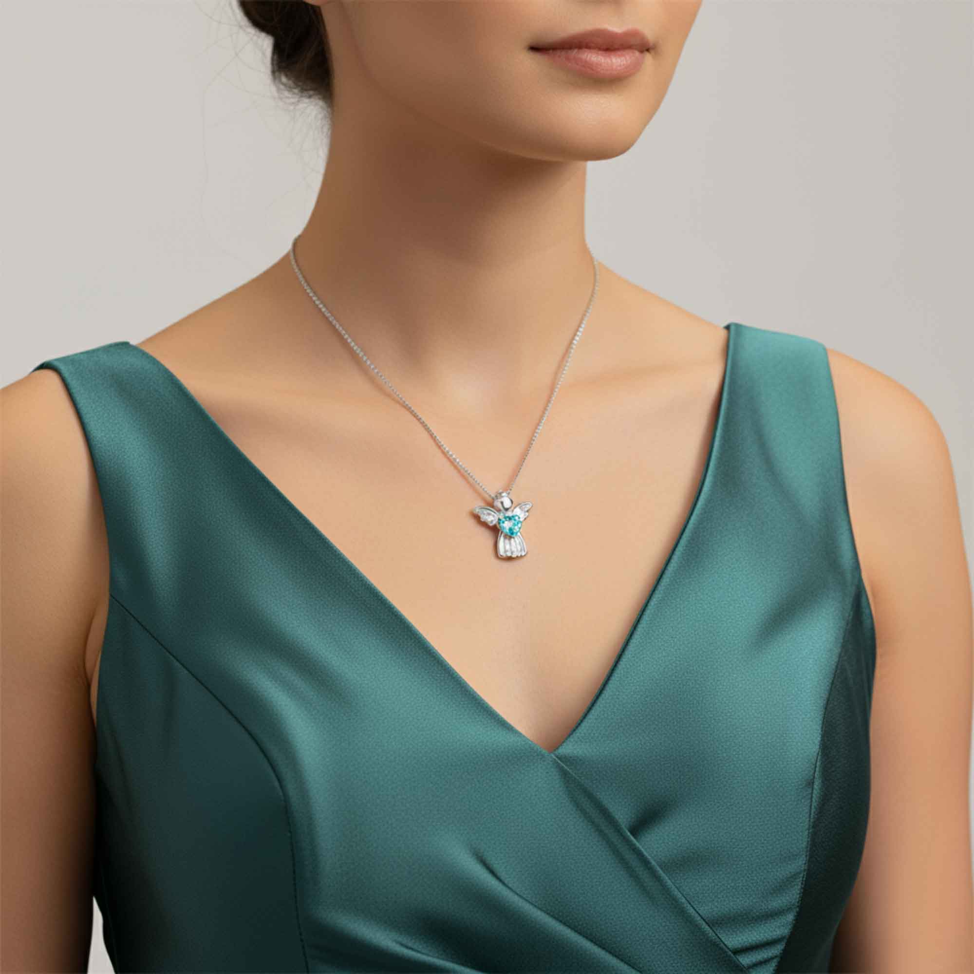 Woman wearing a green dress with a necklace featuring a blue aquamarine pendant.