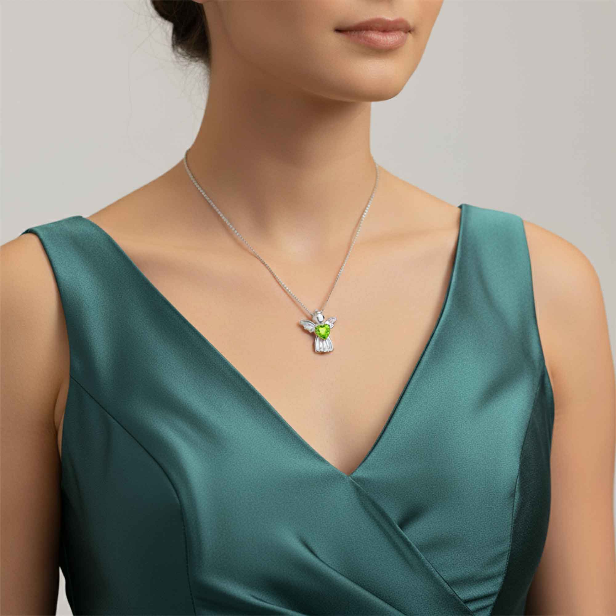 Woman wearing a green dress with a necklace featuring a green peridot gemstone pendant.