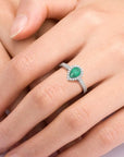 Woman wearing the sterling silver pear-cut emerald halo ring, highlighting its vibrant green gemstone and halo design.
