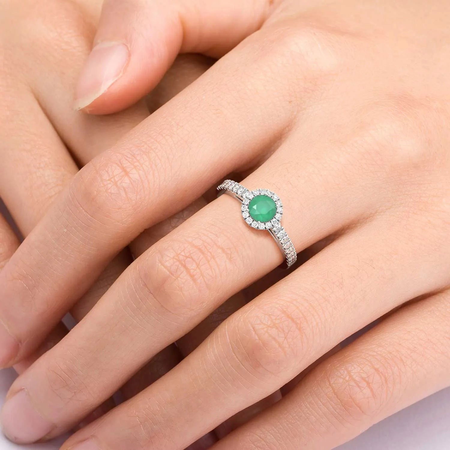 Woman wearing the sterling silver emerald halo ring, showing its elegant fit and radiant green center