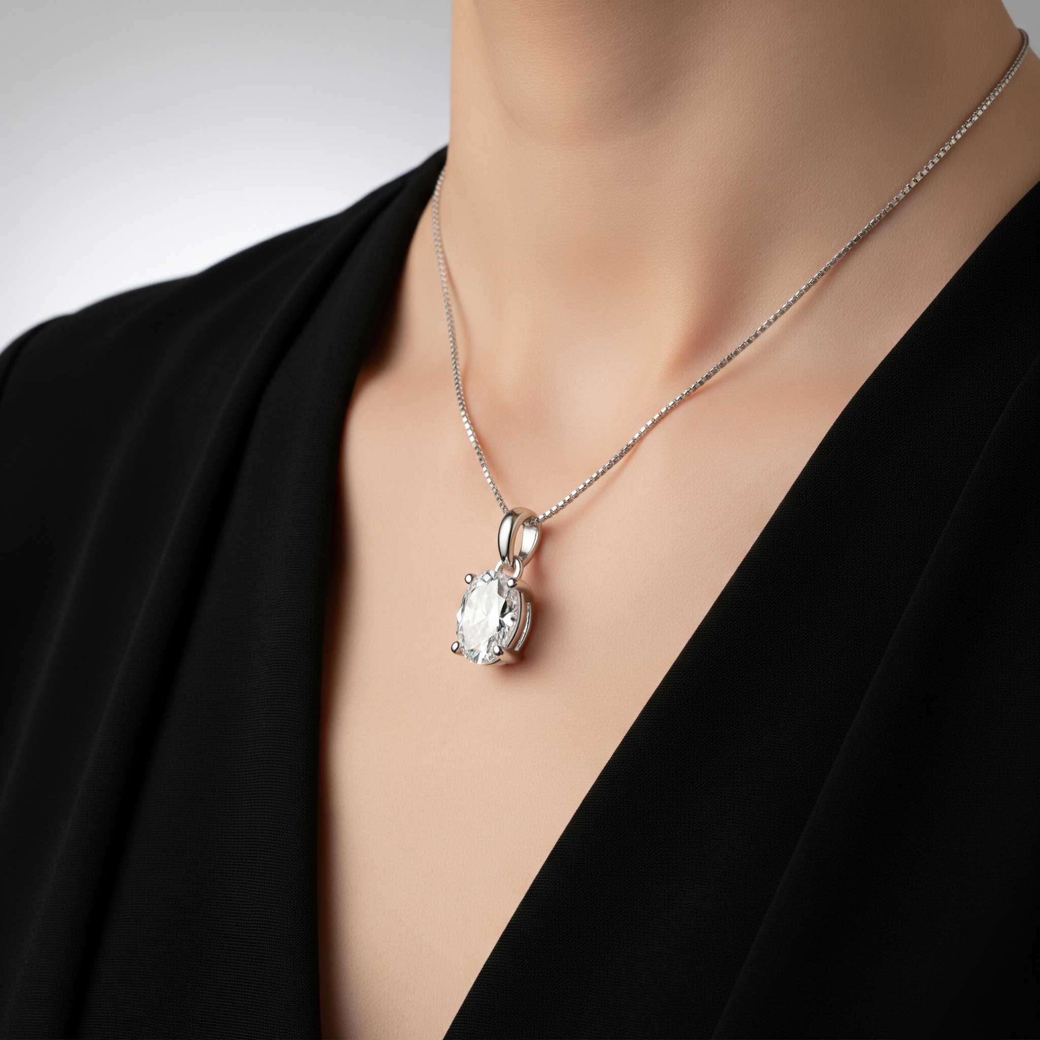 Silver necklace with a pendant on a mannequin wearing a black top.