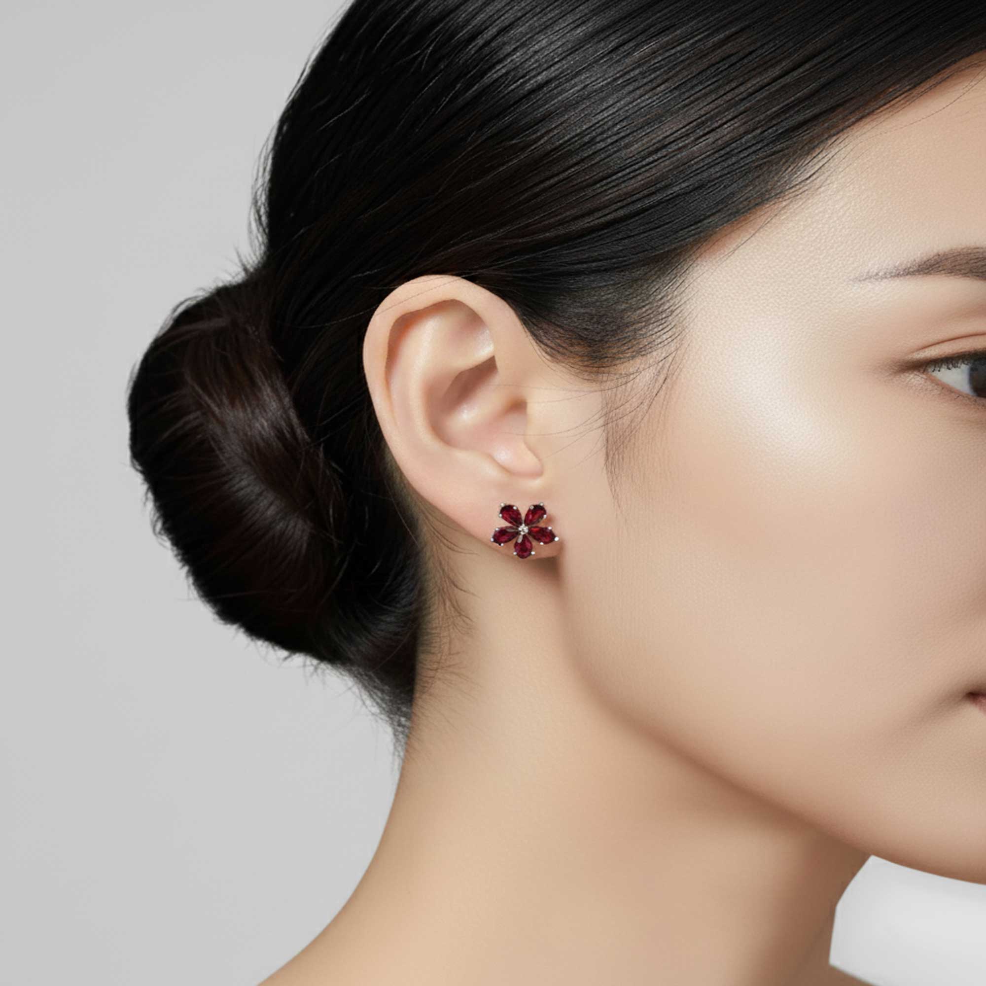 Close-up of a woman wearing red floral earrings with a neutral background