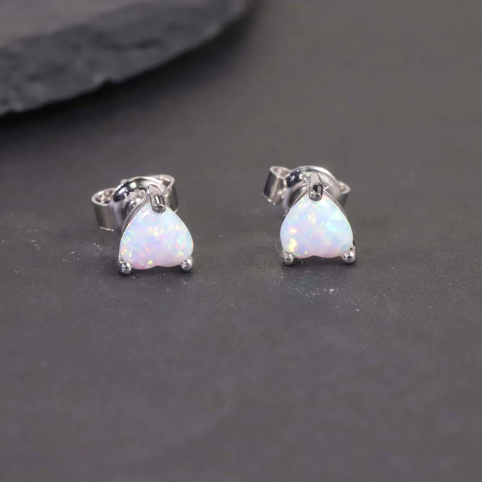 heart opal earrings on black background