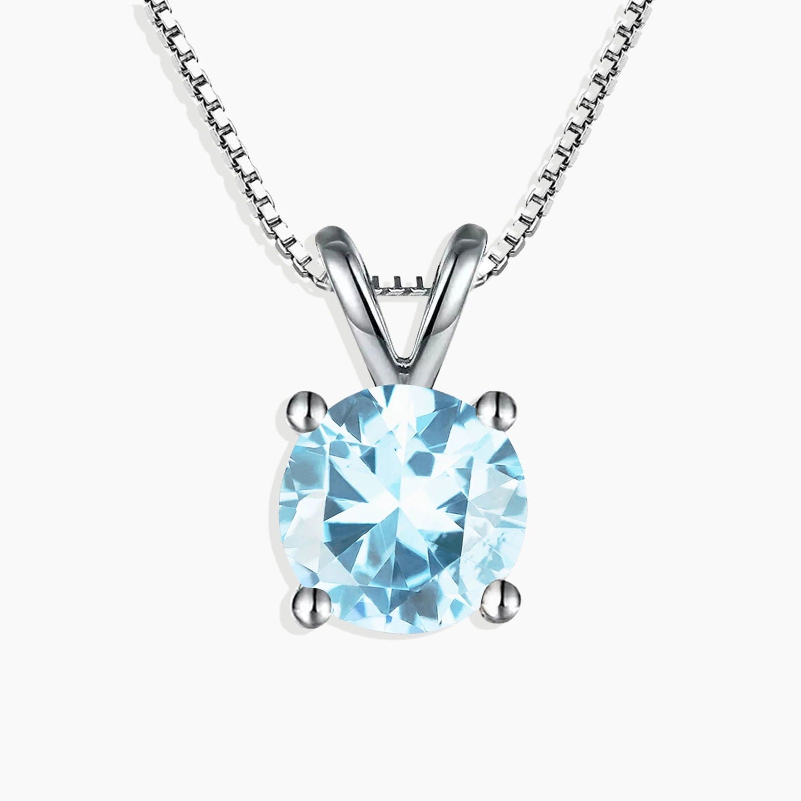 Close-up view of a round-cut aquamarine pendant set in silver with a classic prong design.