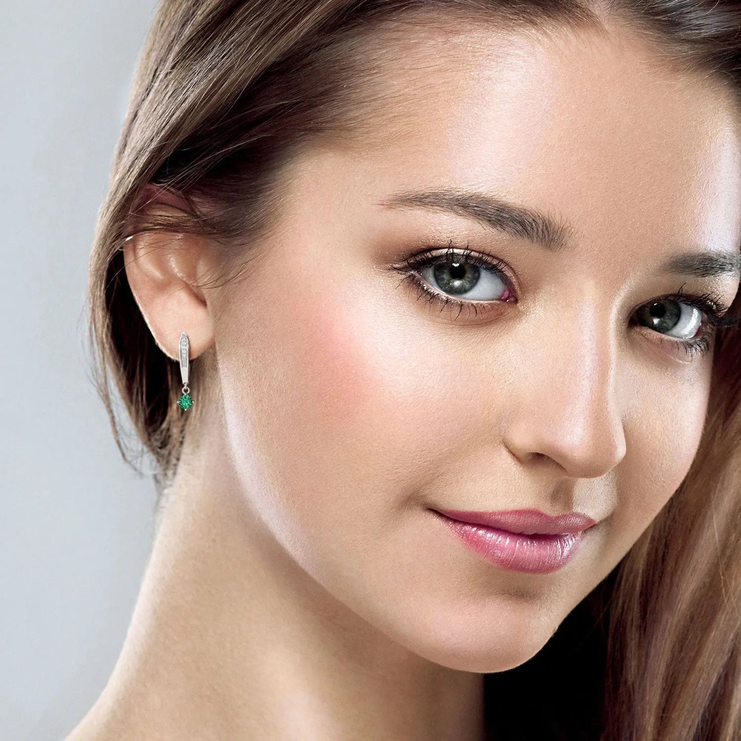 Close-up of a model wearing emerald drop hoop earrings, highlighting their elegant design.