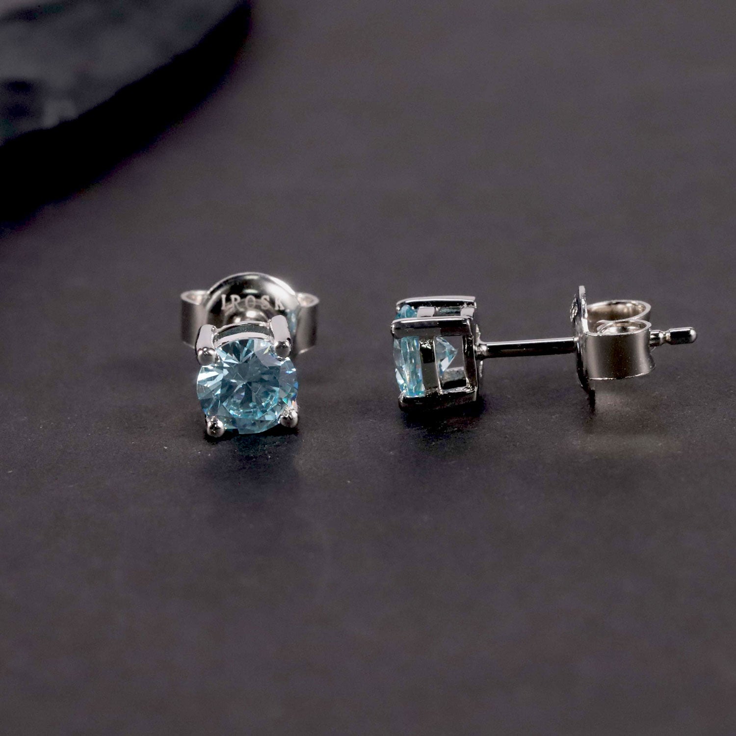 front an side view of aquamarine earrings in contrast to dark background