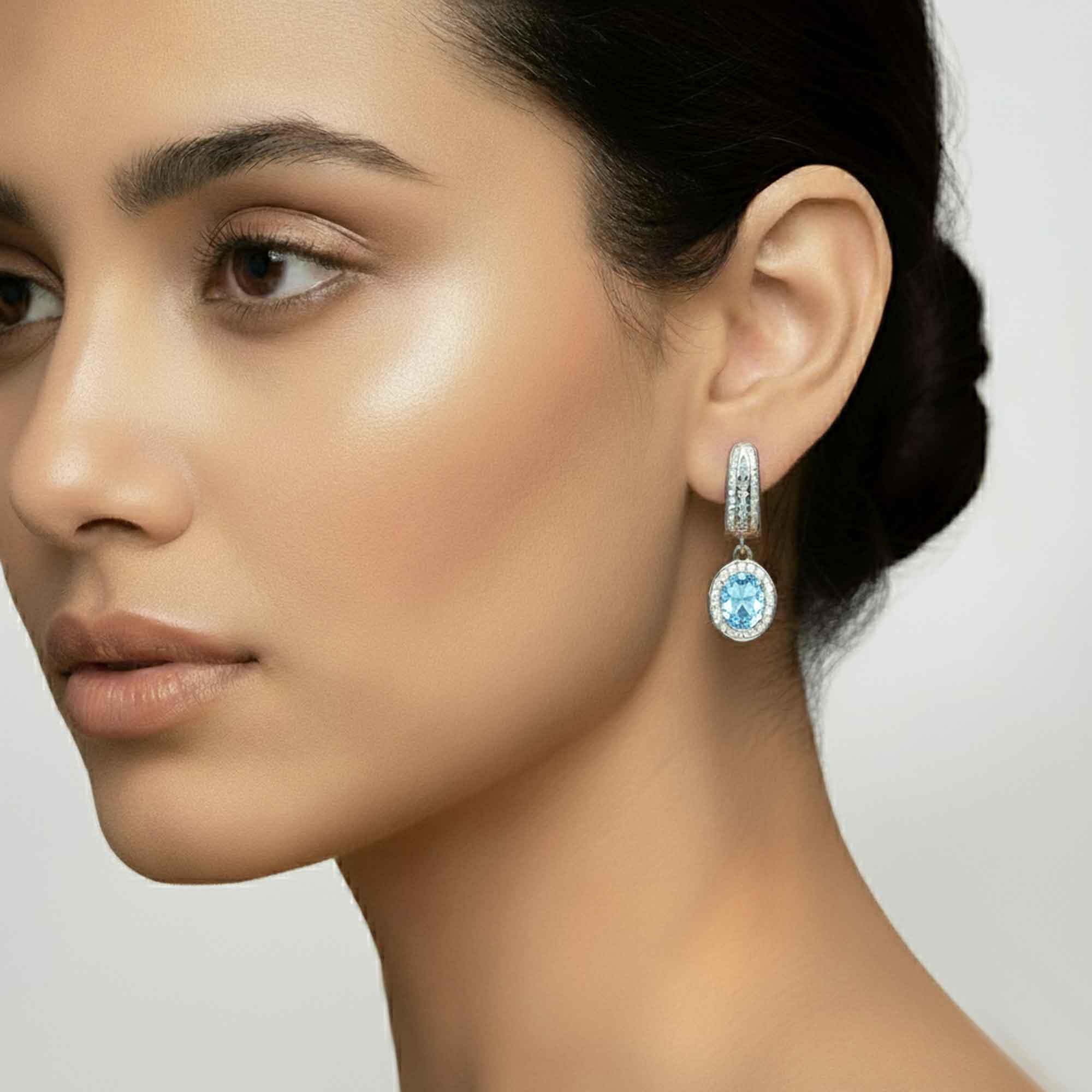 Close-up of a woman wearing a blue gemstone earring with a neutral background