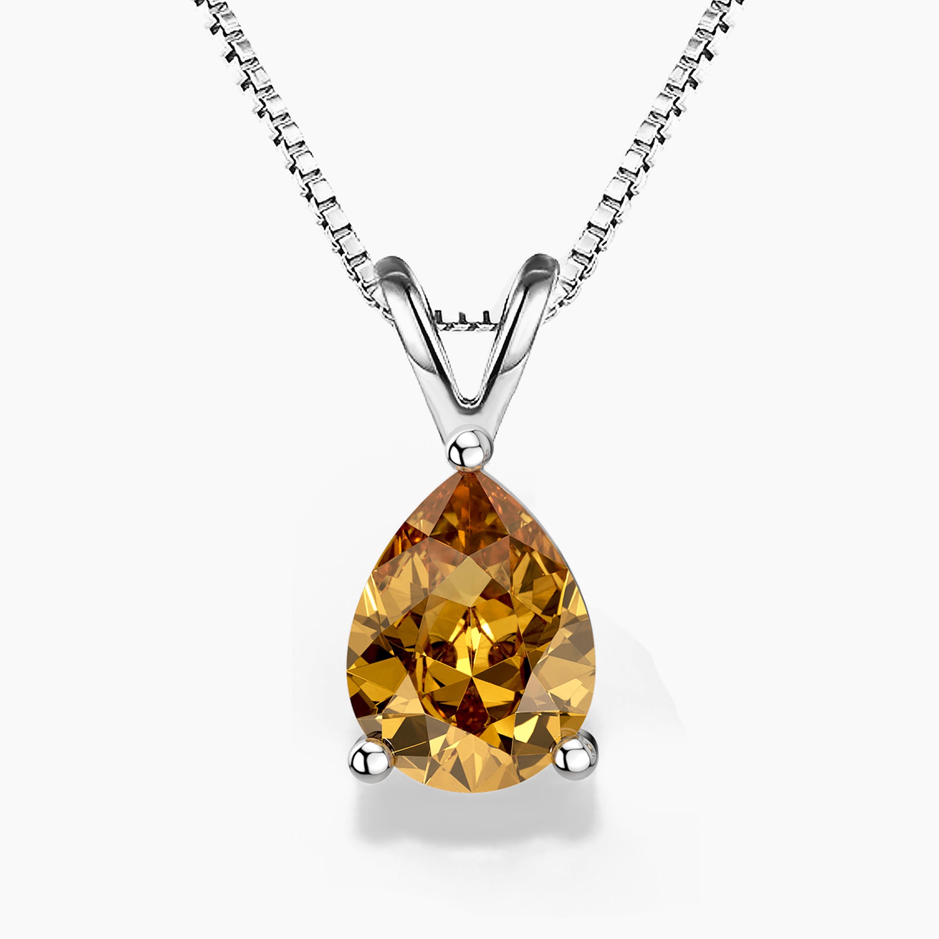 A pear-shaped golden citrine pendant in a three-prong sterling silver setting with a V-shaped bail, hanging from a delicate silver box chain on a white background; the gemstone displays warm amber and honey tones.