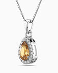 Silver pendant with a teardrop-shaped orange citrine gemstone and smaller clear stones on a white background