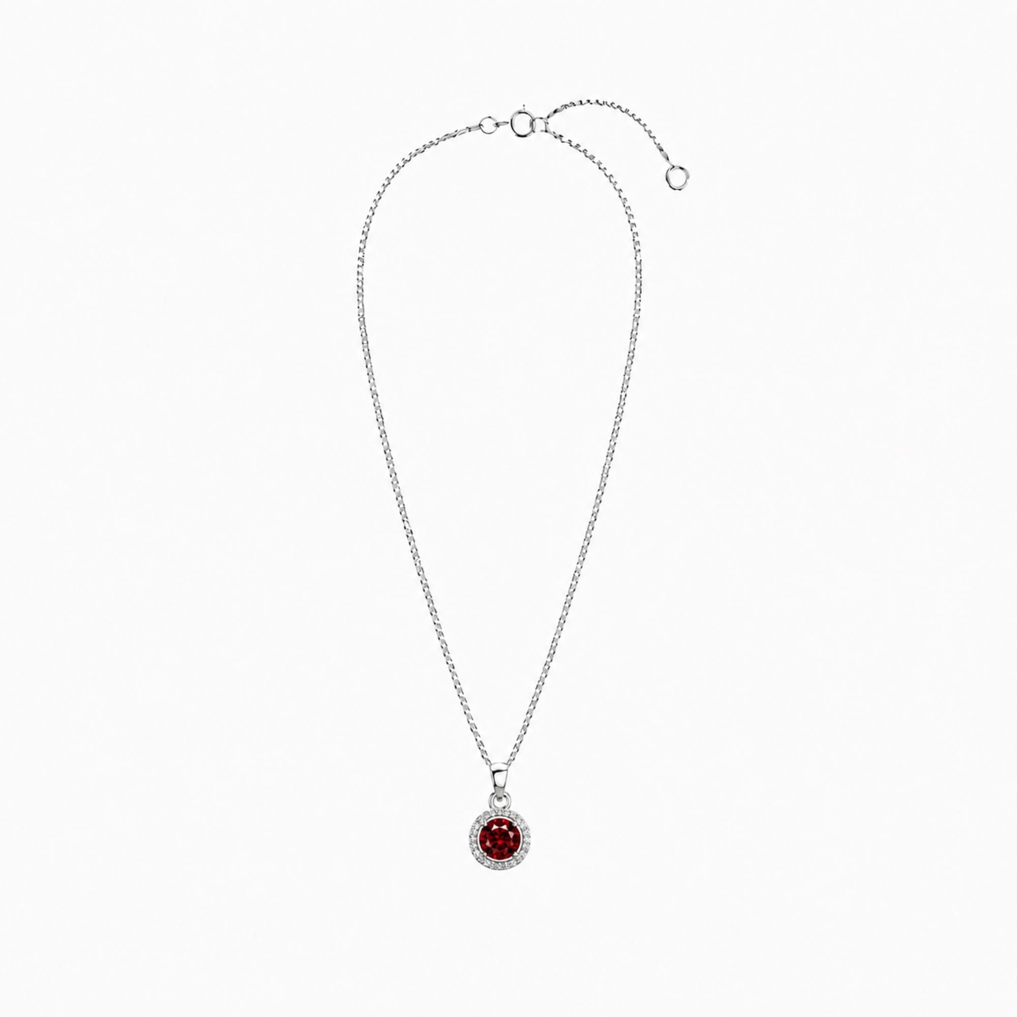 Silver necklace with a red round ruby gemstone pendant with halo on a white background