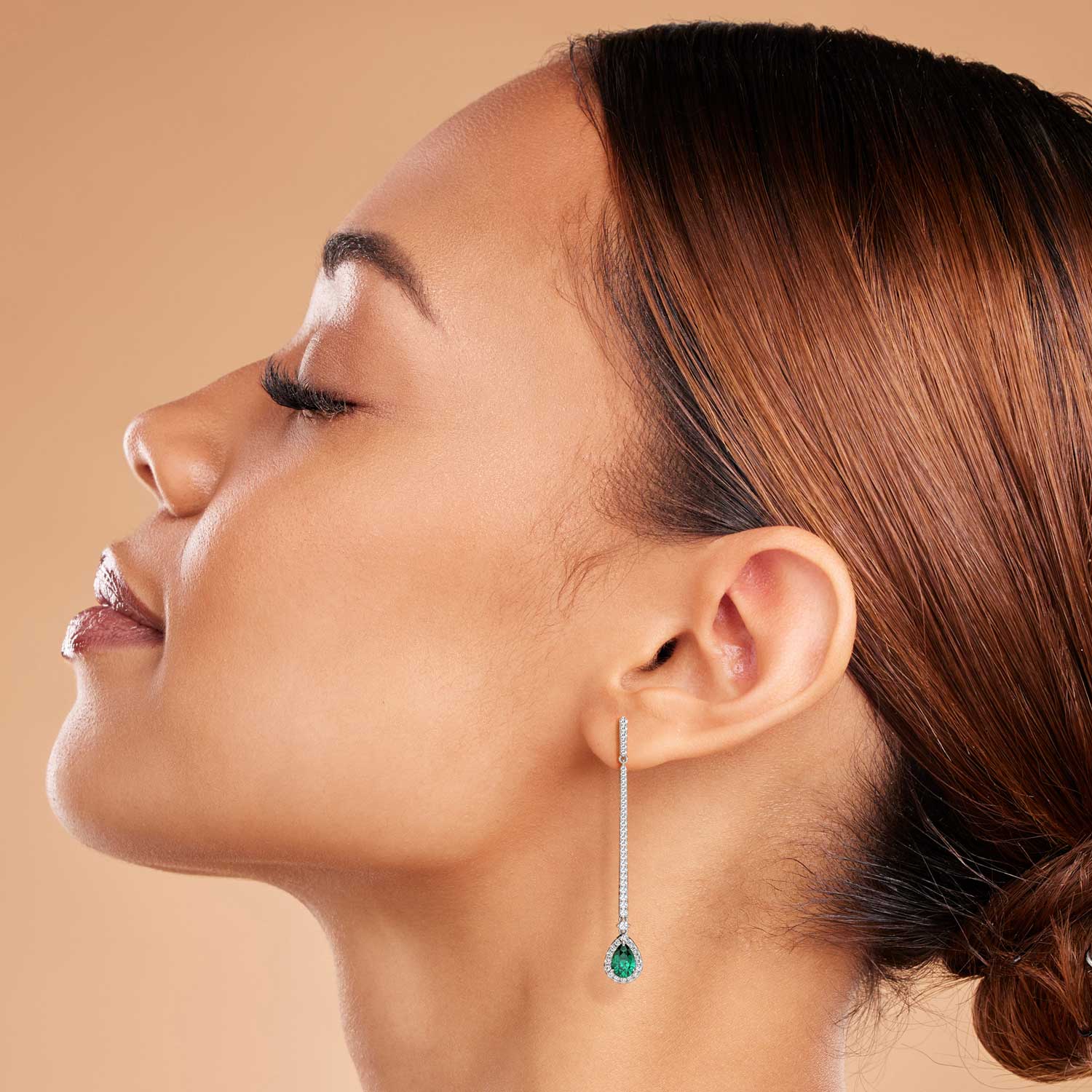 Woman wearing the sterling silver pear-shaped emerald dangle earrings, highlighting their elegant 6 cm drop