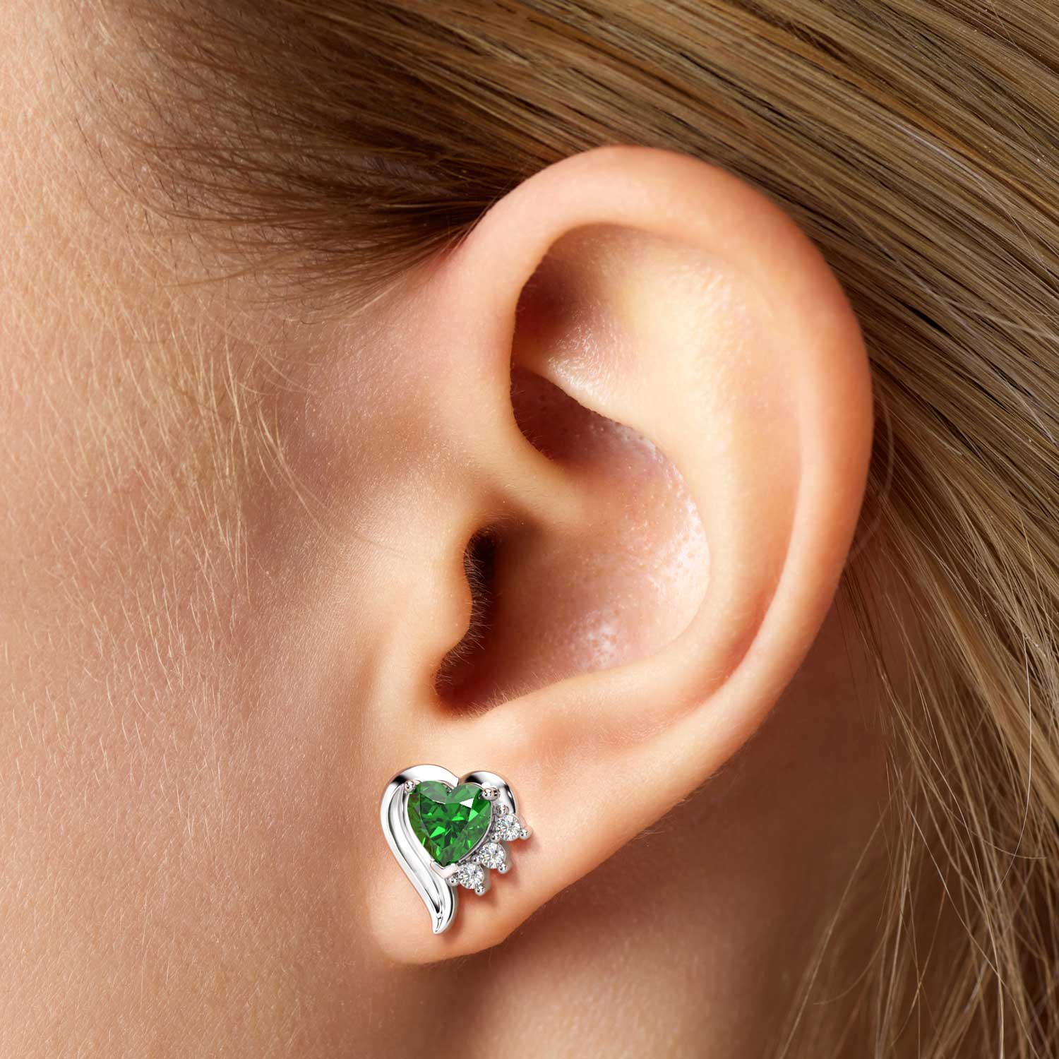 Close-up of a model’s ear wearing the heart-shaped emerald stud earring.