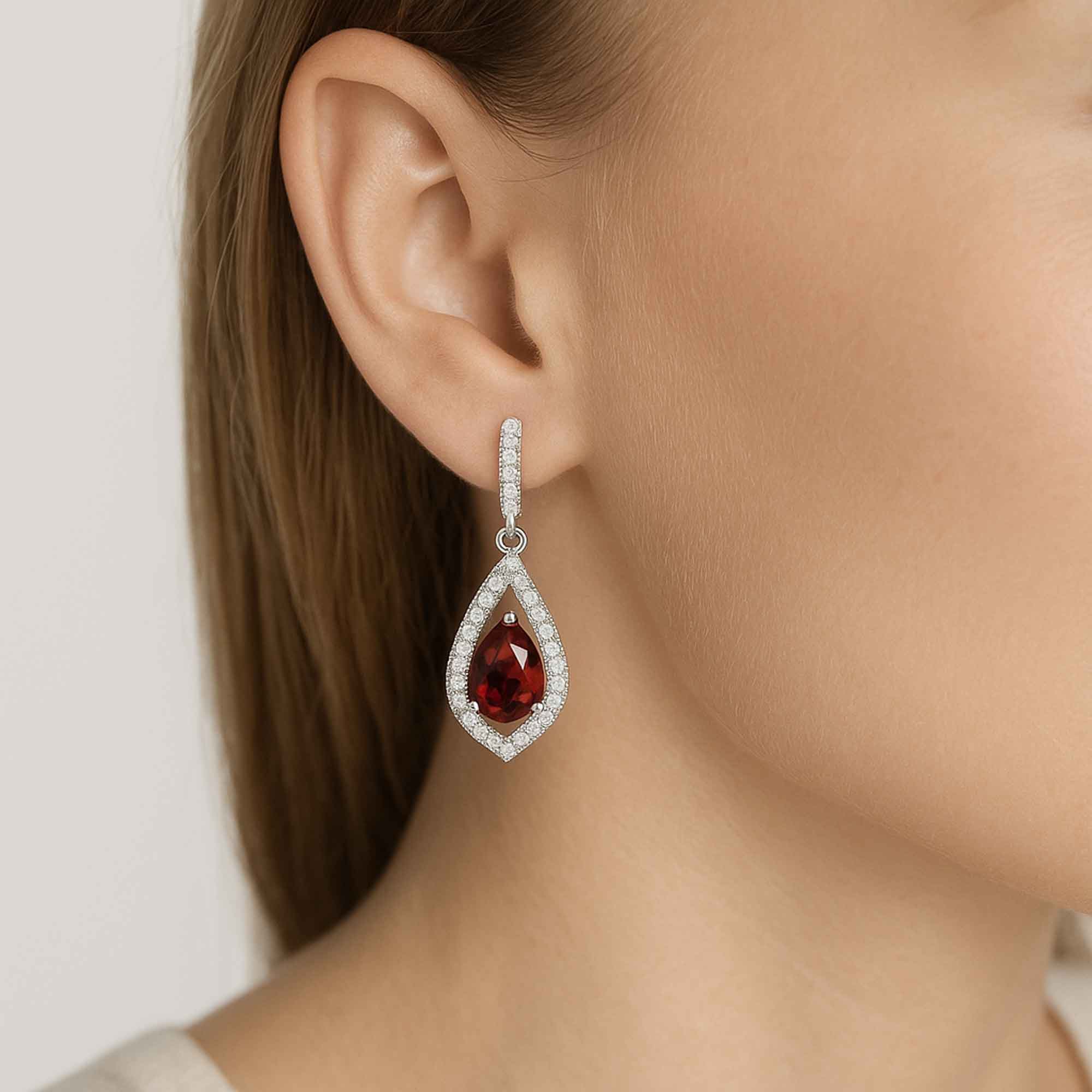 Teardrop-shaped earring with a red garnet gemstone worn by a model.