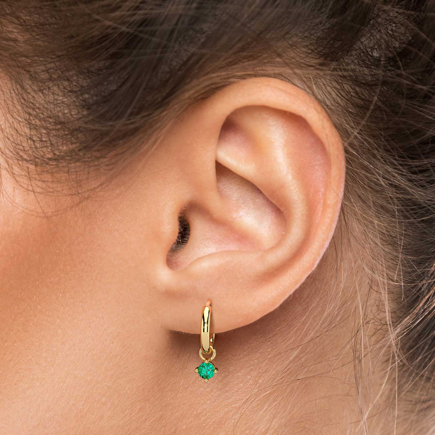 Woman wearing the 18K gold-plated emerald charm hoop earrings, showcasing their vibrant green gemstones and sleek hoop design.