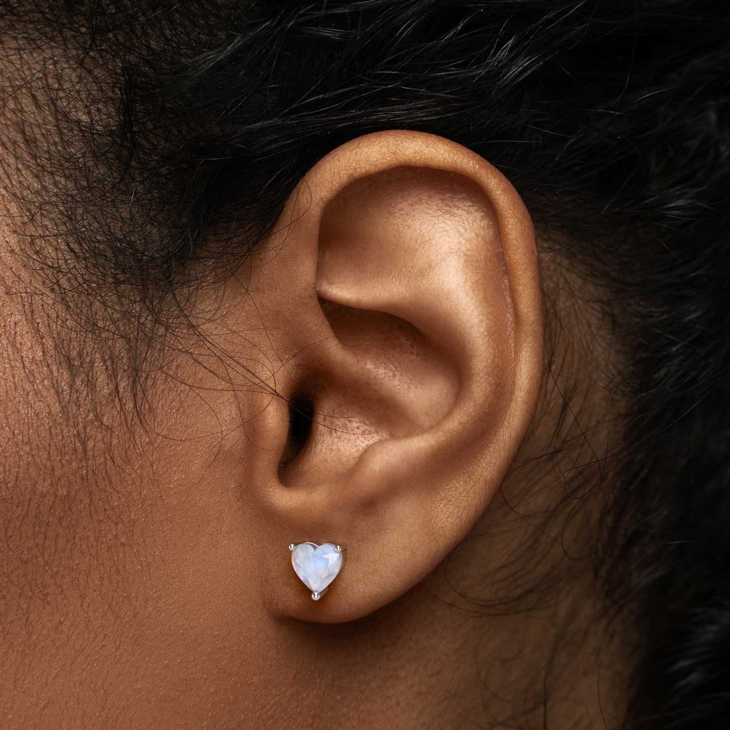 Heart-shaped moonstone stud earring worn on ear – natural June birthstone jewellery in sterling silver