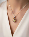 Necklace with a yellow gemstone pendant on a mannequin wearing a white top.