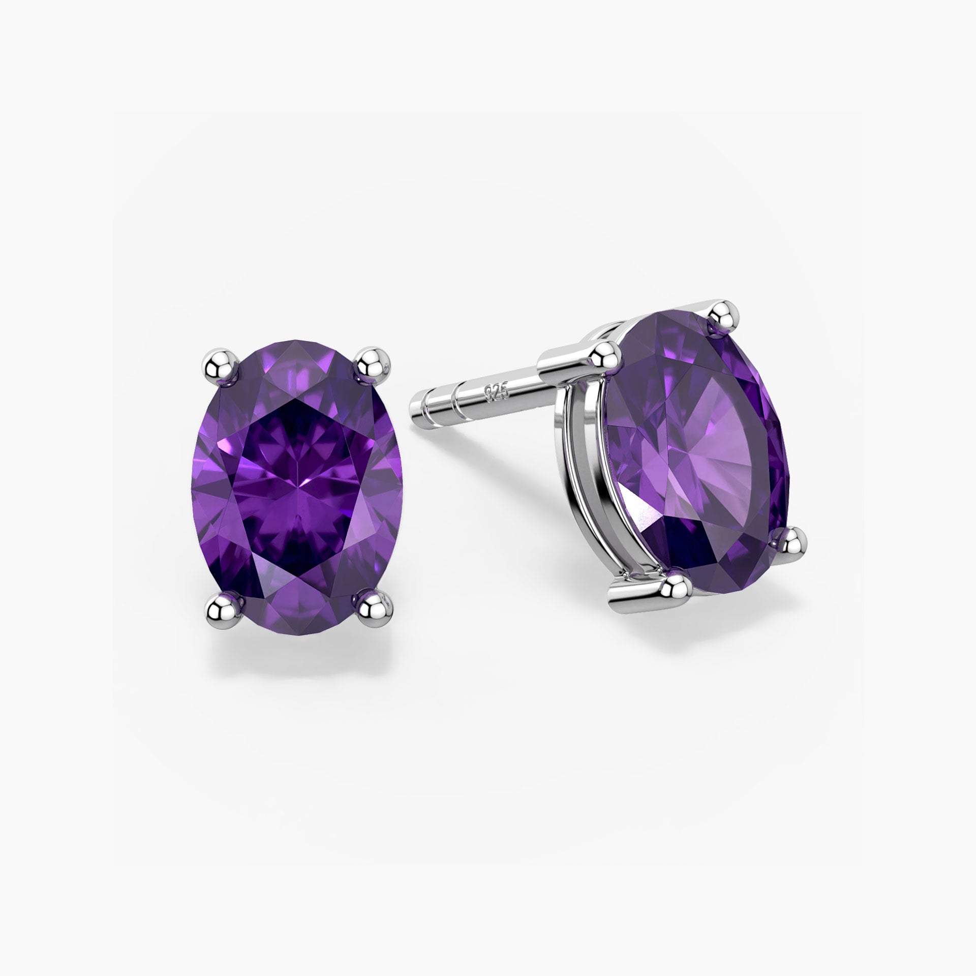 Pair of oval-cut vibrant purple amethyst stud earrings in a four-prong silver setting with push-back closures, displayed on a white background.