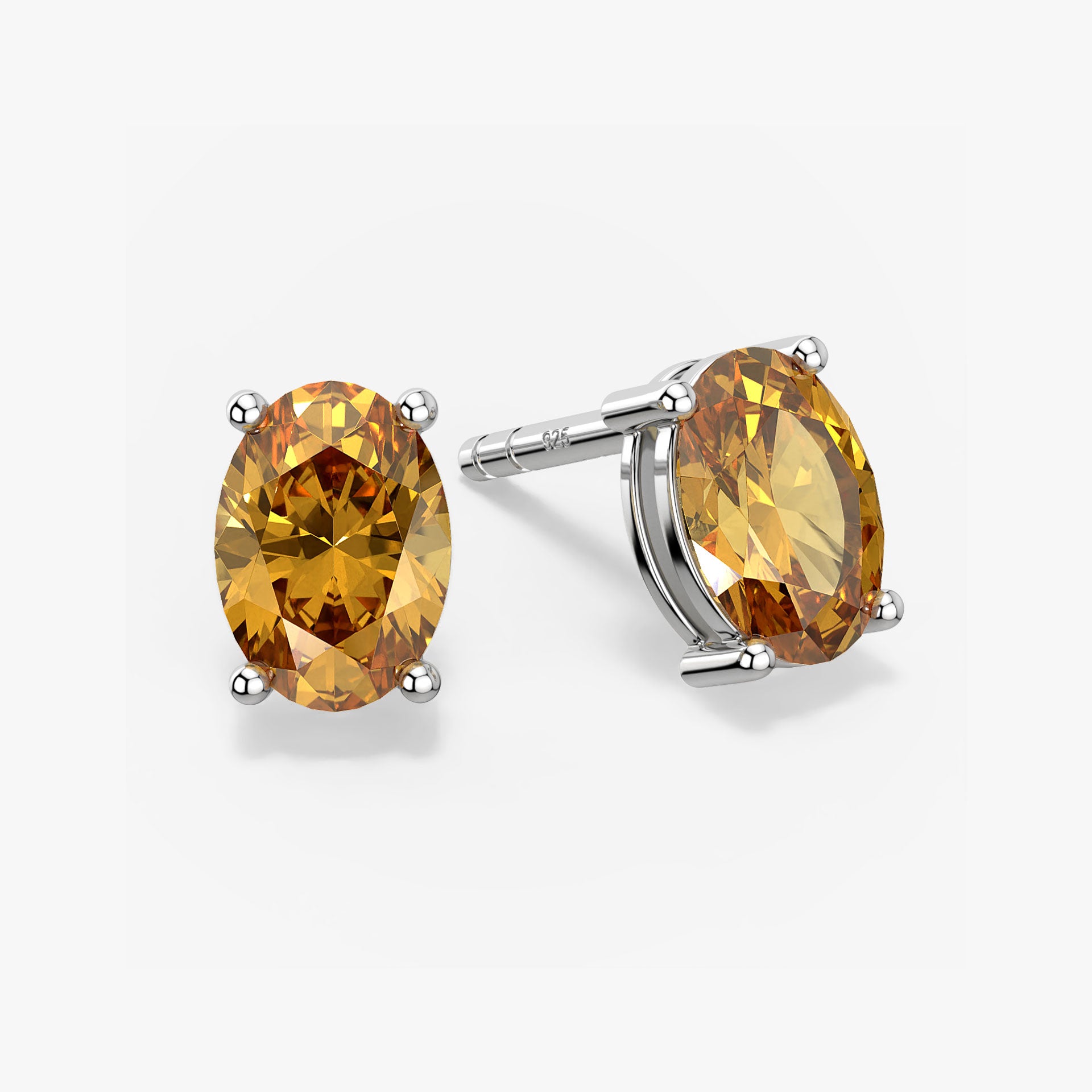 Pair of oval-cut golden yellow citrine stud earrings in a four-prong silver setting with push-back closures, displayed on a white background
