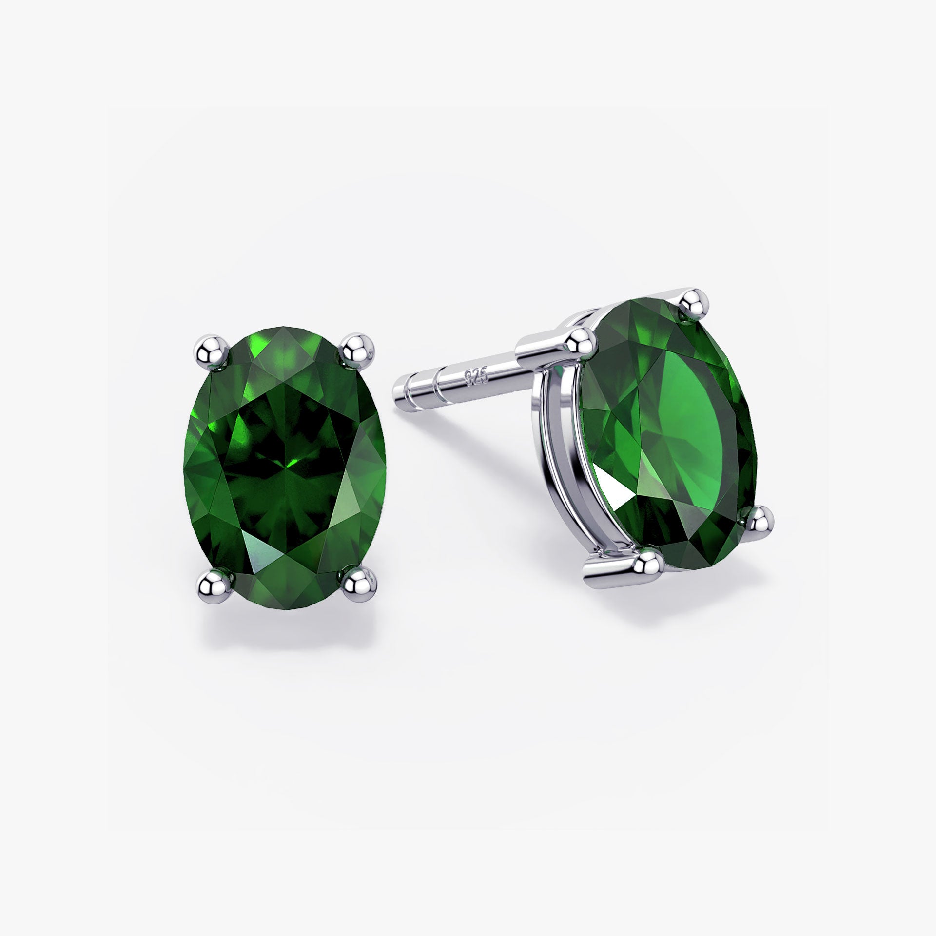 Pair of oval-cut deep green gemstone stud earrings in a four-prong silver setting with push-back closures, displayed on a white background.
