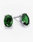 Pair of oval-cut deep green gemstone stud earrings in a four-prong silver setting with push-back closures, displayed on a white background.
