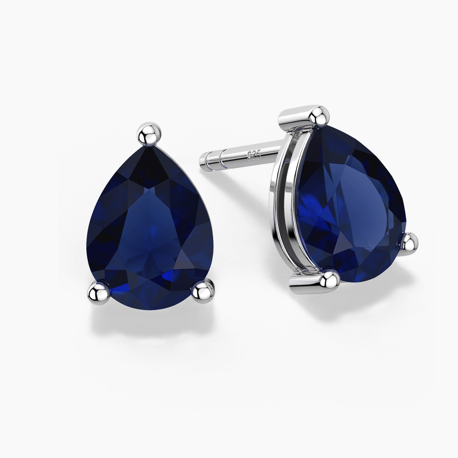 ChatGPT said:
Alt: Two pear-shaped deep-blue sapphire gemstones set as sterling silver stud earrings, one shown head-on and the other at a slight angle, each held by three polished prongs on a white background.