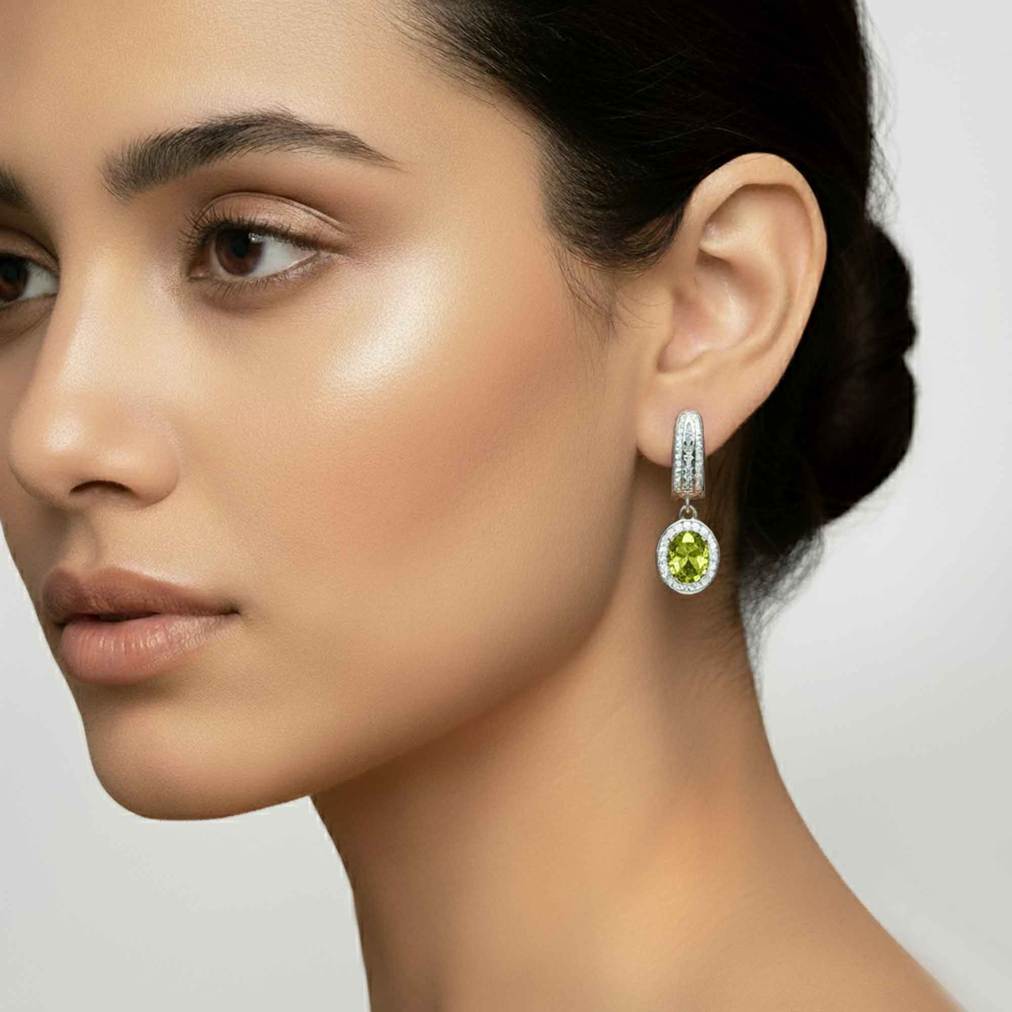 Close-up of a woman wearing a green peridot gemstone earring with a neutral background