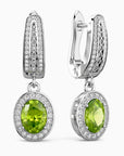 Pair of earrings with green gemstones and silver accents on a white background