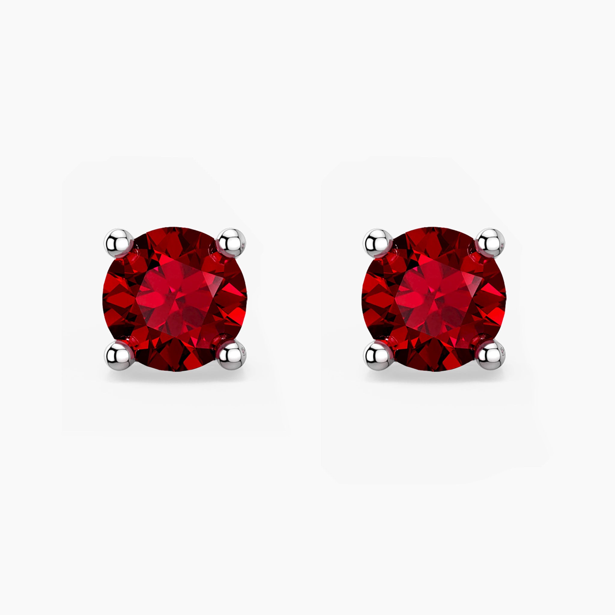 Pair of red ruby gemstone stud earrings on a white background