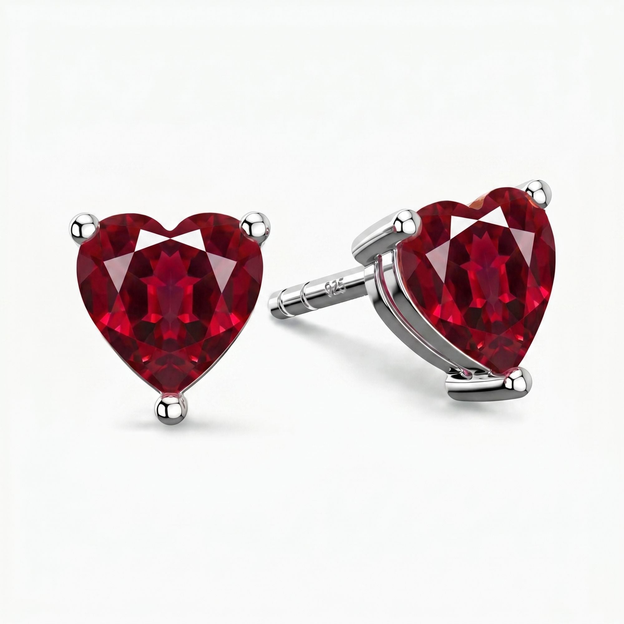 side view of heart-shaped red ruby gemstone earrings on a white background