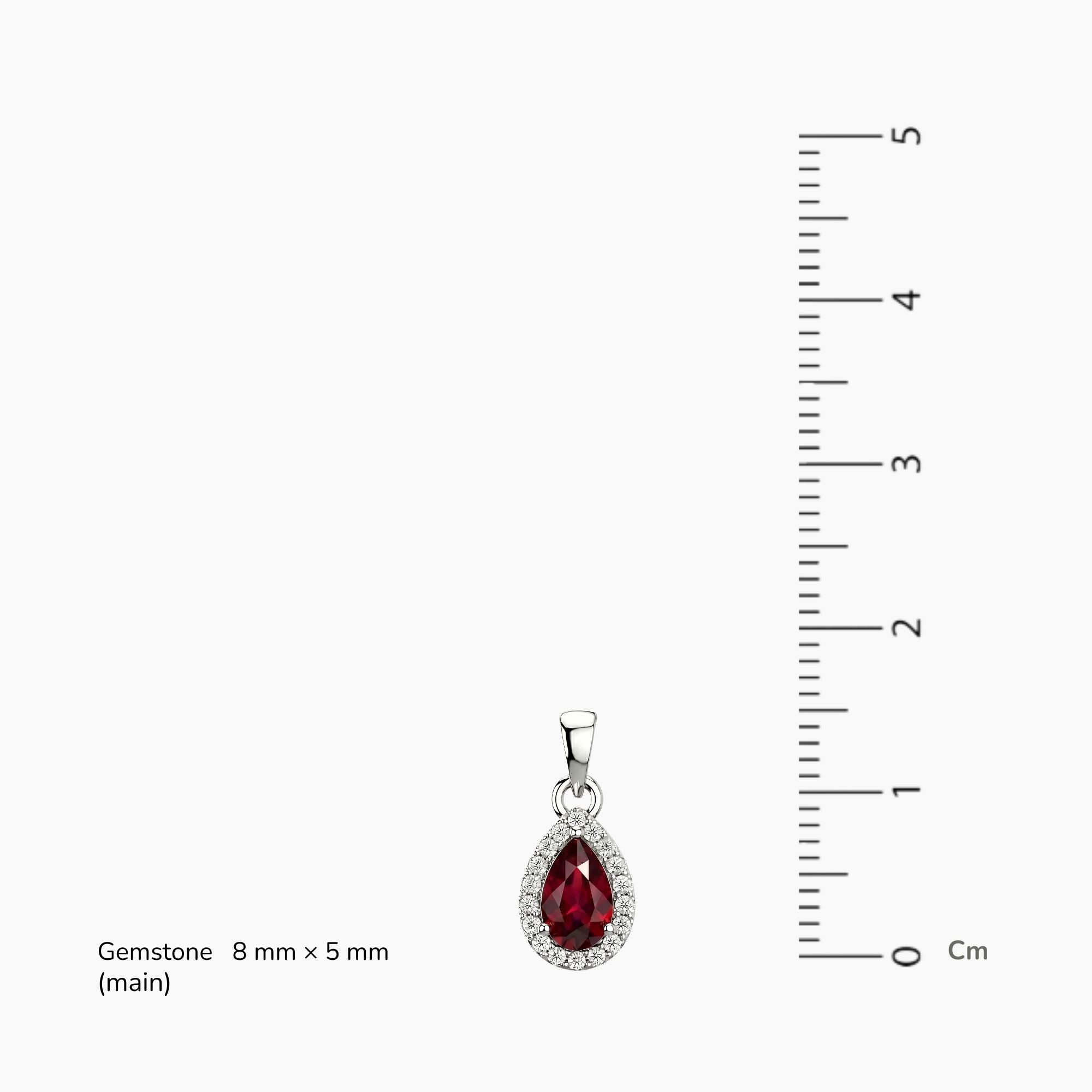 Teardrop-shaped ruby halo pendant with red gemstone and silver setting, next to a ruler for scale.