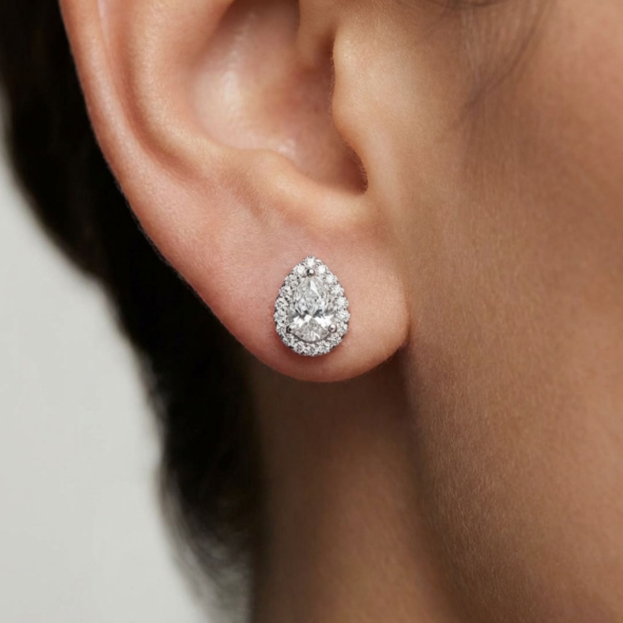 Close-up of an ear wearing a sparkling moissanite earring against a neutral background -april birthstone earrings