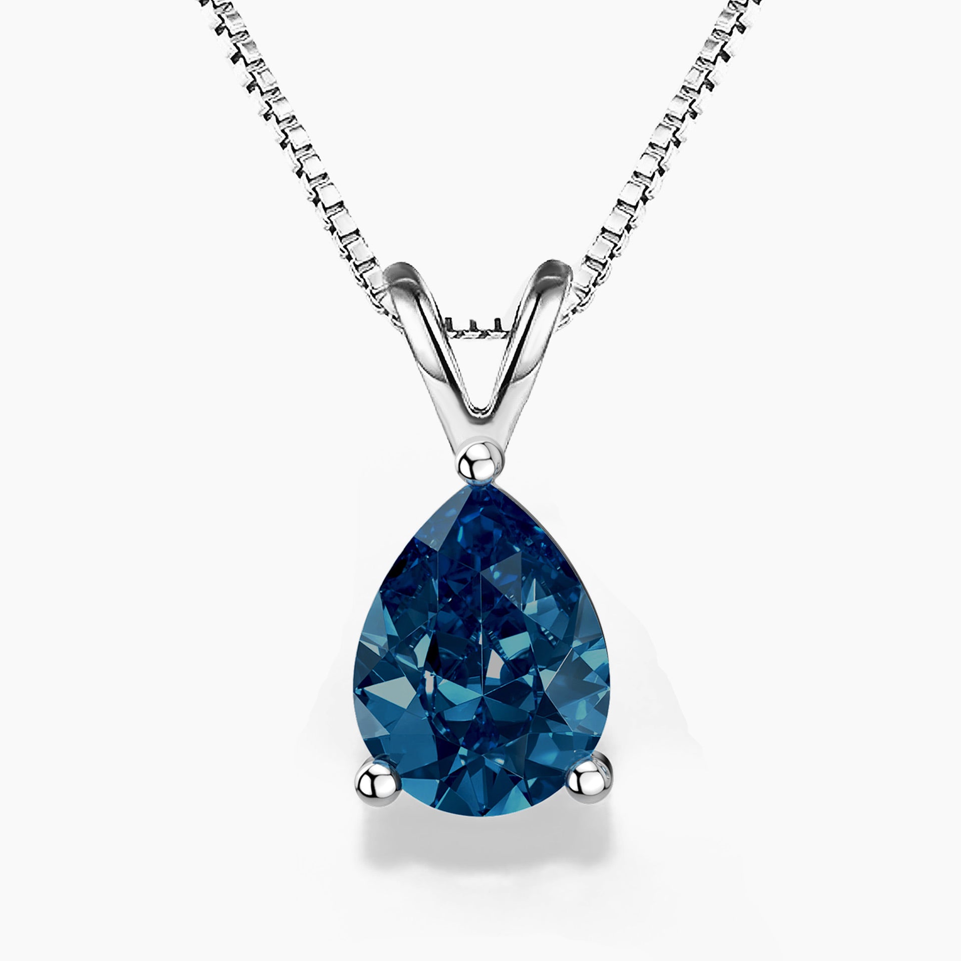 A pear-shaped London blue topaz pendant set in a three-prong sterling silver setting with a V-shaped bail, suspended from a delicate silver box chain; the gemstone showcases deep ocean-blue tones with brilliant faceting, against a white background.