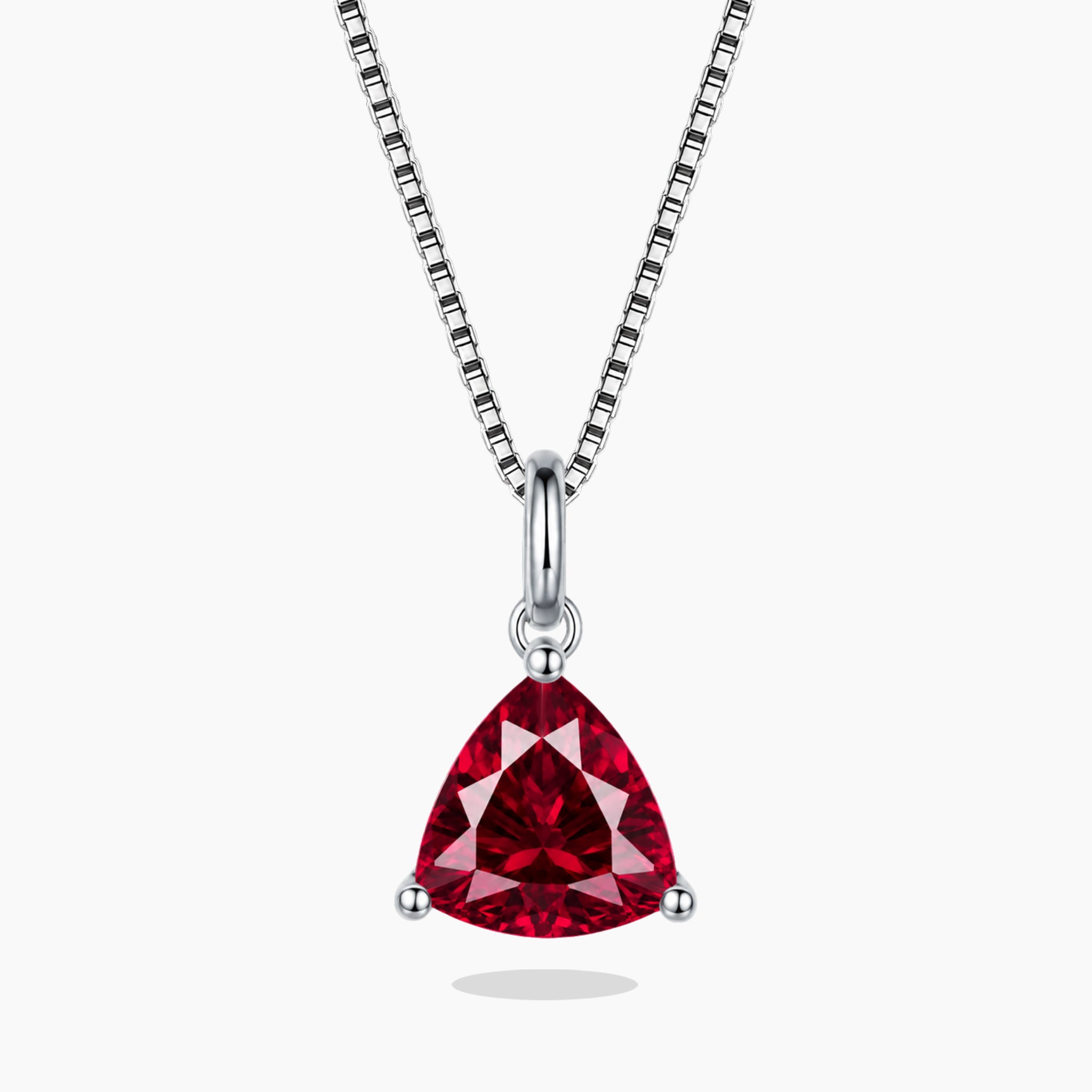 Red gemstone pendant on a silver chain against a white background