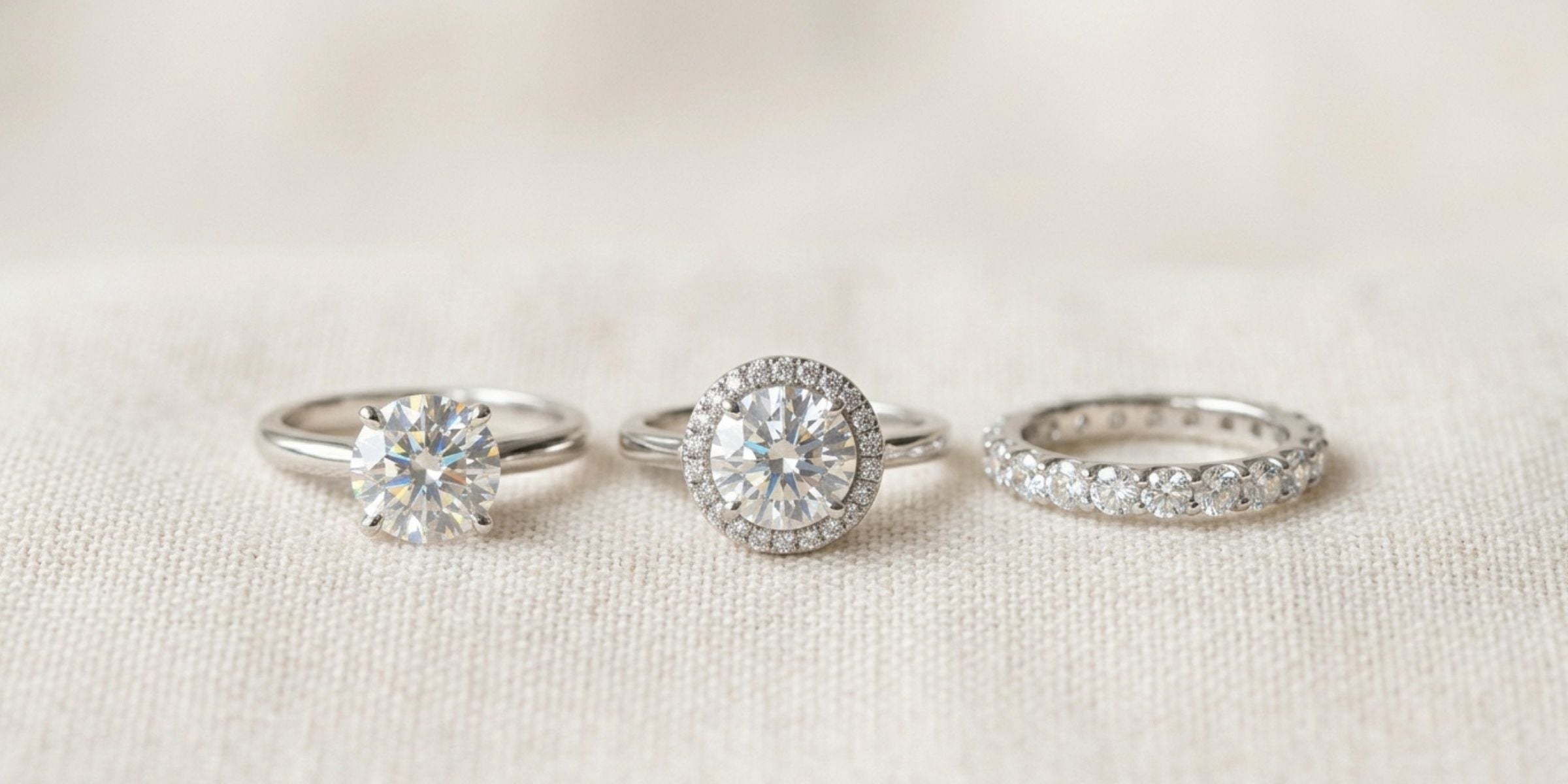 Sterling silver solitaire, halo and eternity moissanite rings in a row on linen