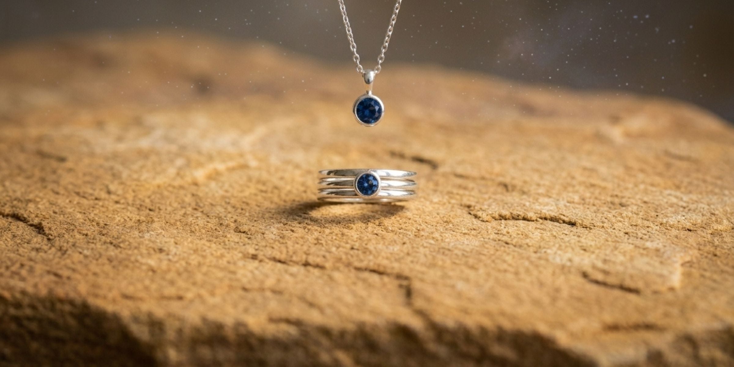Sterling silver sapphire necklace and ring on stone with a soft starlit background
