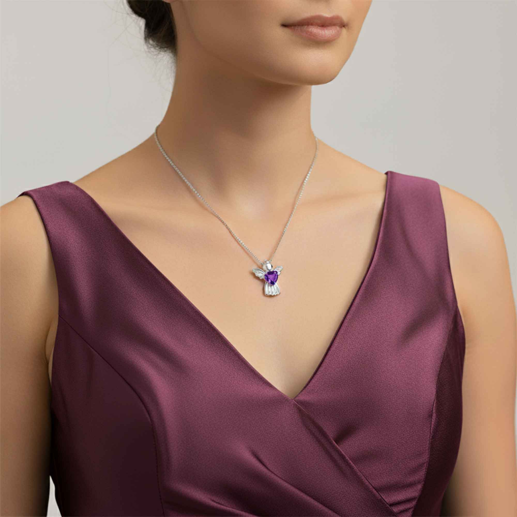 Woman wearing a purple dress with a necklace featuring a amethyst angel pendant