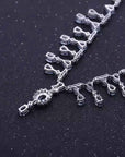 Silver necklace with intricate design on a dark background