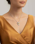 Woman wearing a gold dress with a silver necklace featuring a yellow citrine gemstone pendant.