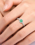 Woman wearing the sterling silver emerald halo ring, showing its elegant fit and radiant green center