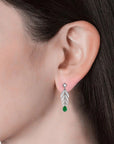 Close-up of a model’s ear wearing the feather-inspired emerald drop earrings.
