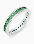 Angled view of the emerald channel-set ring in rhodium-plated sterling silver, highlighting the row of green stones.