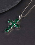 Close-up of the oval emerald cross pendant resting on a dark surface.