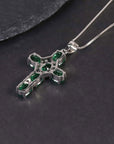 Alternate angle showing the emerald cross pendant against a dark surface.