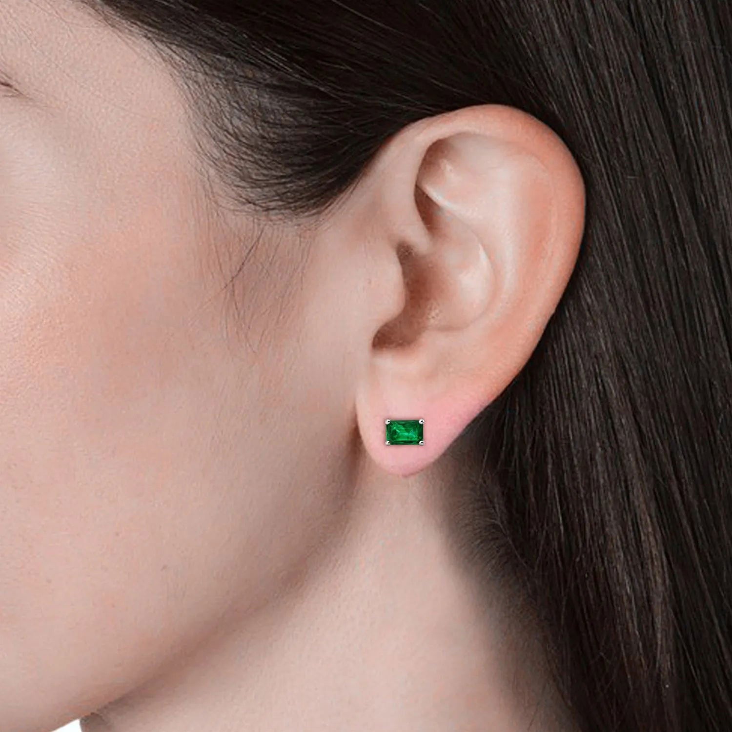 Side view of the emerald-cut emerald stud earrings laid horizontally, showing their prong settings.