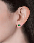 Side view of the emerald-cut emerald stud earrings laid horizontally, showing their prong settings.